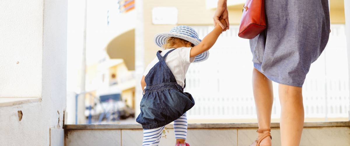 Back view of beautiful toddler girl walk with mother, stairs outdoors background, closeup view