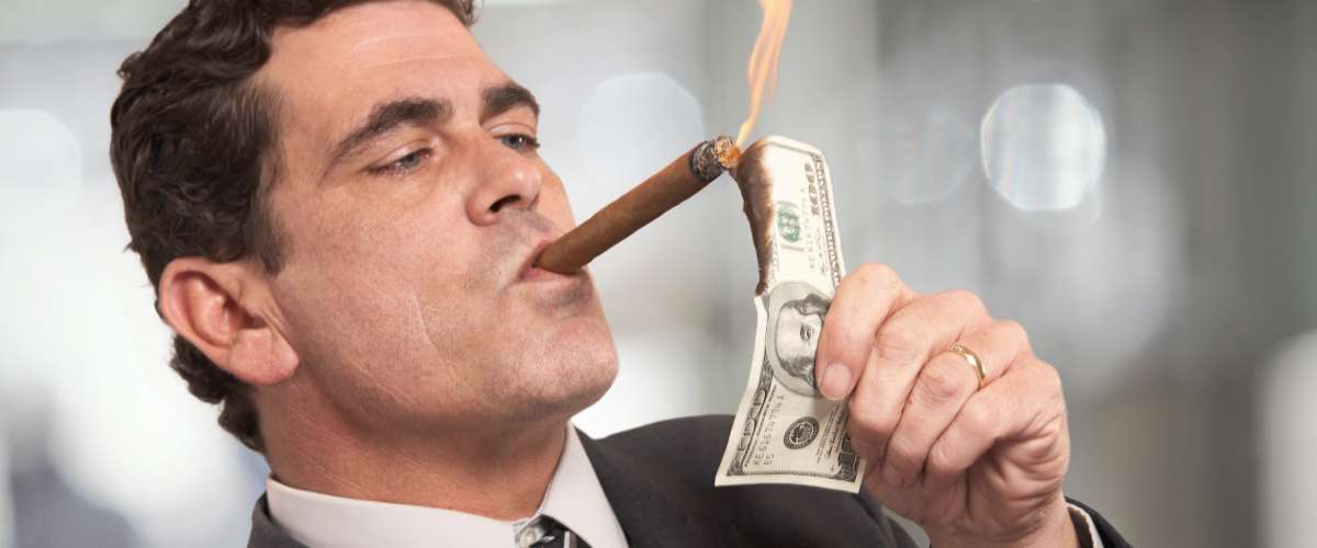 rich banker lighting a cigar with a $100 bill