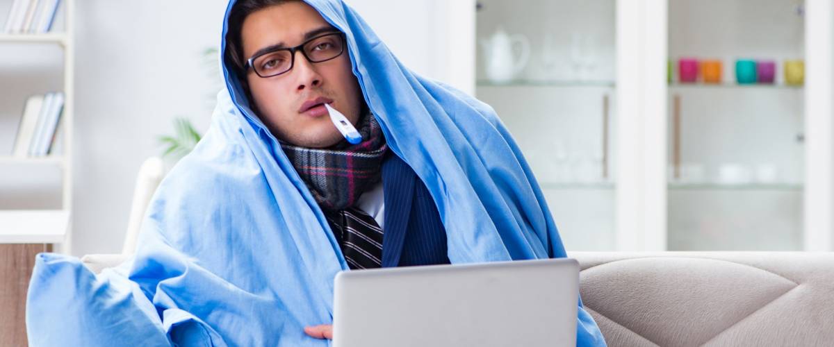 Sick businessman working from home due to flu sickness