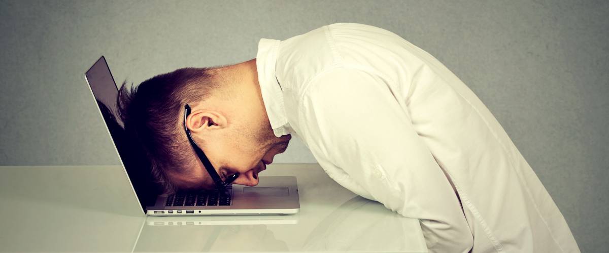Desperate employee, stressed young man resting head on laptop keyboard