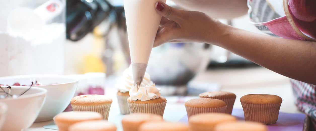 Young woman icing cupcakes in her kitchen