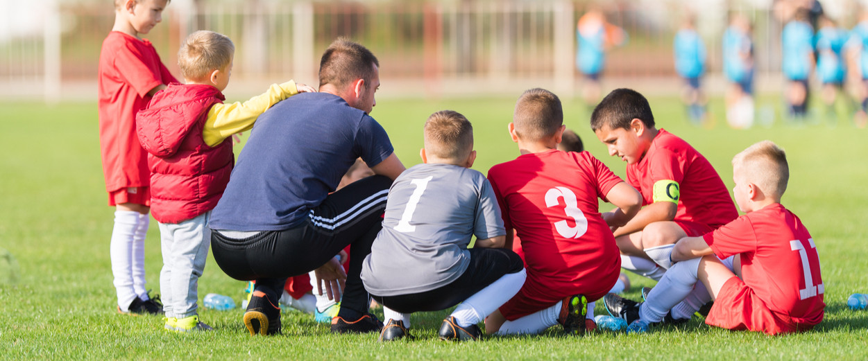 Young man coaching kids soccer