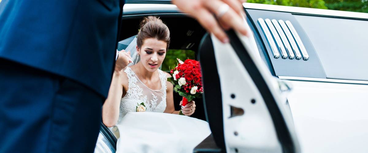 Bride exiting a white limousine
