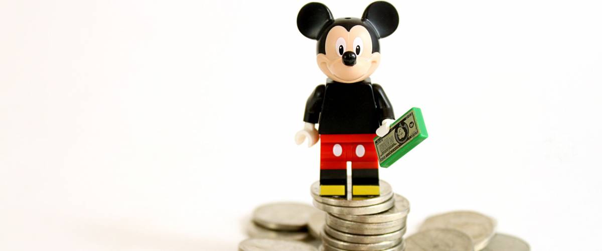 Colorado, USA - May 13, 2016: Studio shot of LEGO minifigure Mickey Mouse on top of a pile of money isolated on white background.