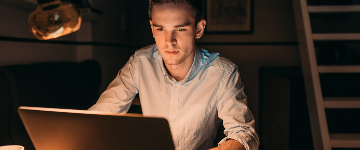 Young man working on his laptop late in the evening