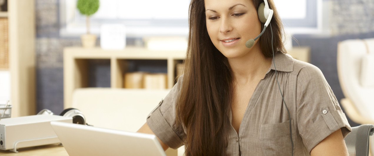 Young woman taking calls from home with a headset