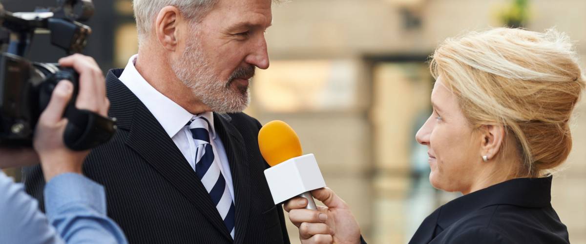 Female Journalist With Microphone Interviewing Businessman