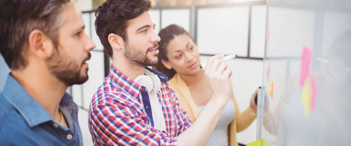 Businessman with young partners looking at whiteboard in creative office