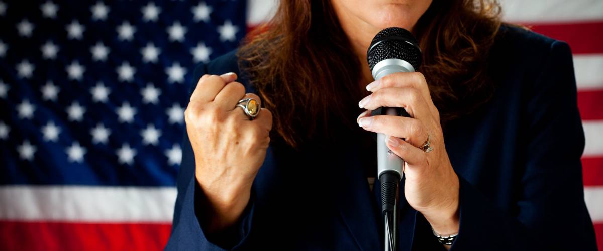 Politician: Woman Speaking Strongly At Microphone