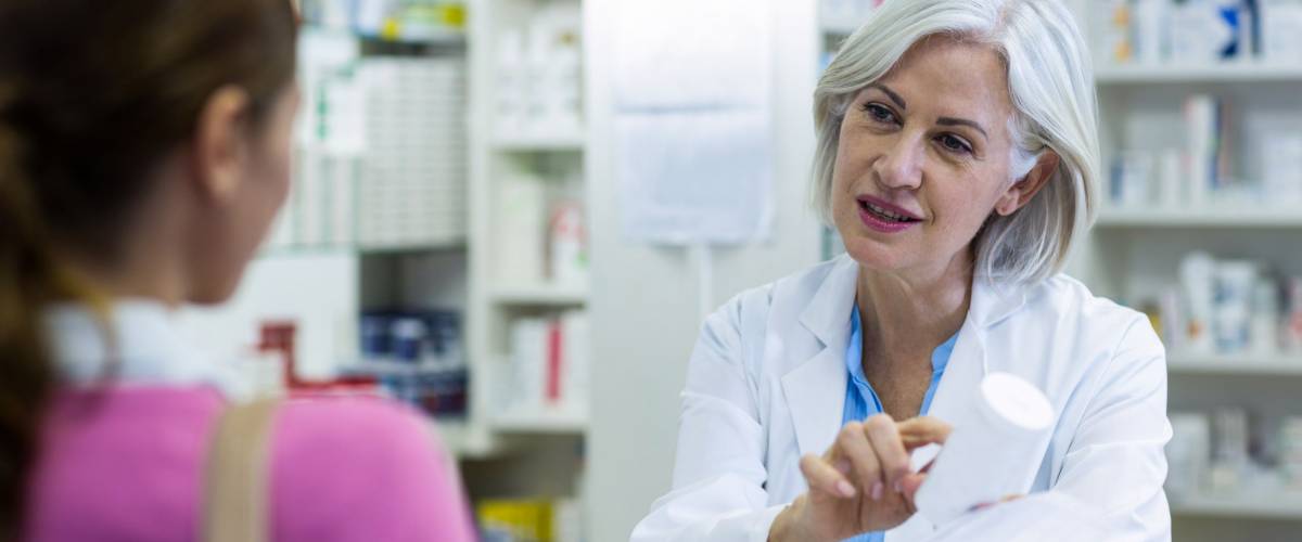 Pharmacist assisting the bottle of drug to customer in pharmacy