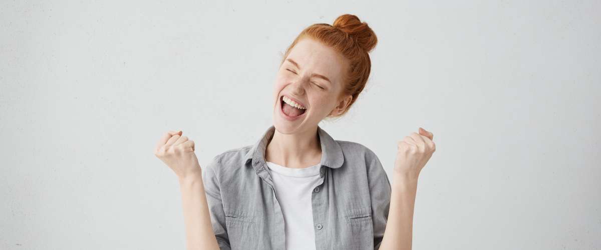 Excited young woman with red hair feeling rewarded