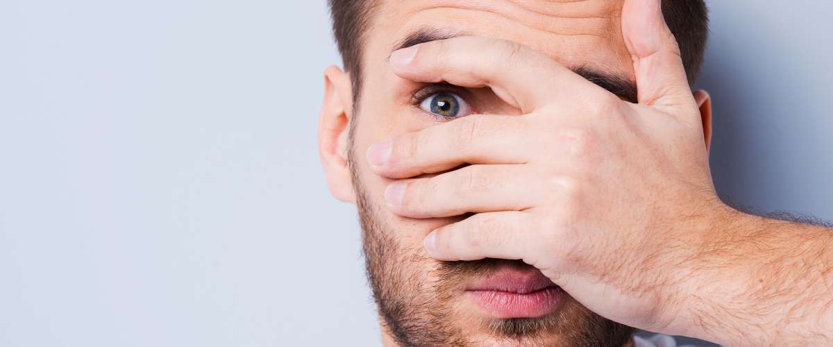 man looking through fingers