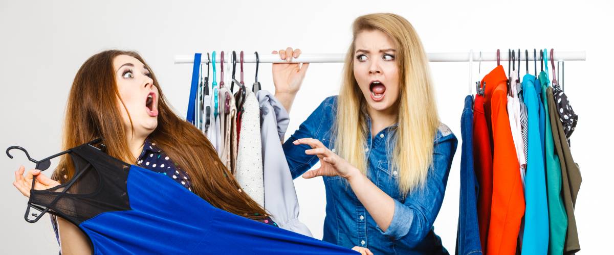 two women fight over clothes on a clothing rack