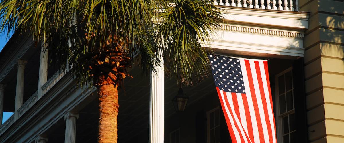 A historic Antebellum home flies the American flag.