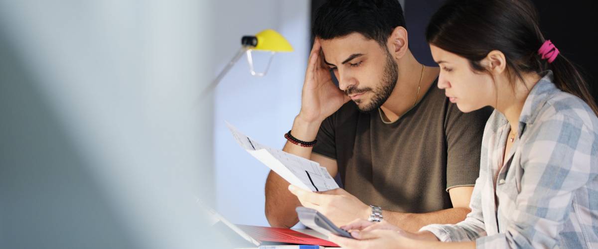 Young couple reviewing invoices and doing family business plan. Concept of money and economic problem for man and woman living together