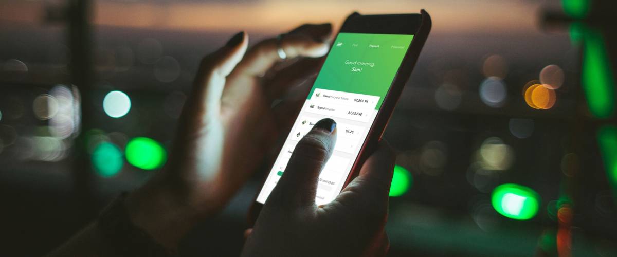 A person using the Acorns app at night.