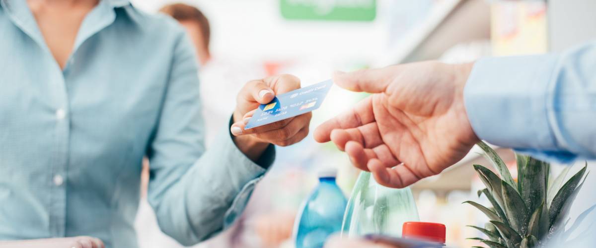 Woman at the supermarket checkout, she is paying using a credit card