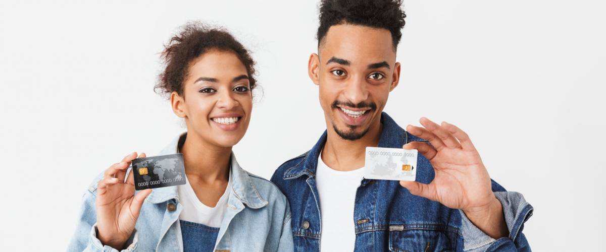 smiling couple holding up two credit cards