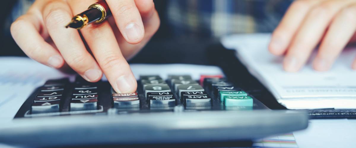 Man holding a fountain pen calculates costs.
