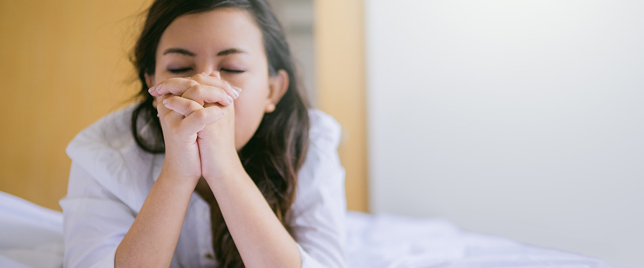 Young woman praying on bed