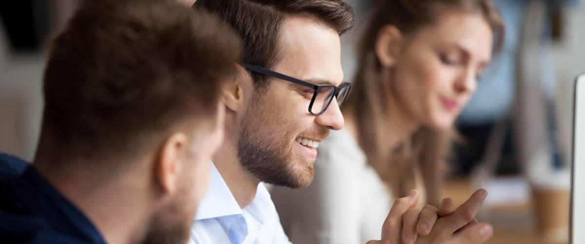 Close up of male colleagues cooperating in coworking office space talking laughing together
