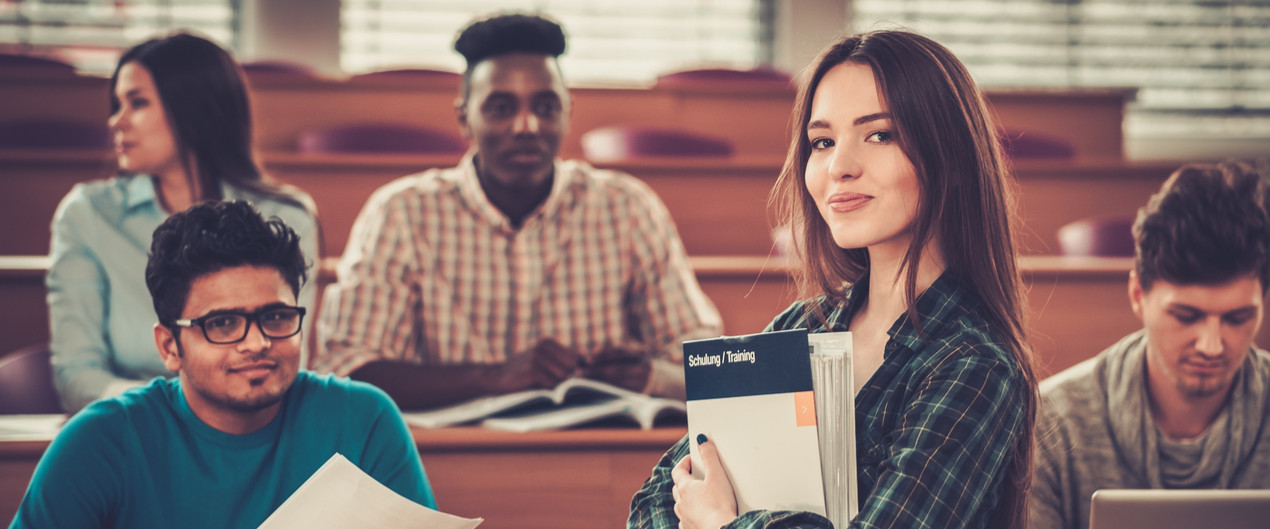 Multinational group of cheerful students taking an active part in a lesson while sitting in a lecture hall.