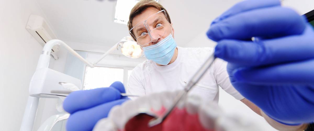 Stomatology. Dentist over open patient's mouth looking in teeth. Inside vew