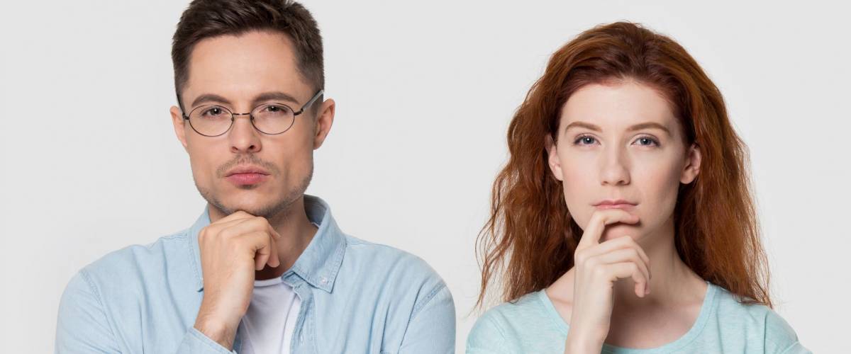 Pensive millennial couple stand isolated on grey studio background touch chin with finger thinking of something