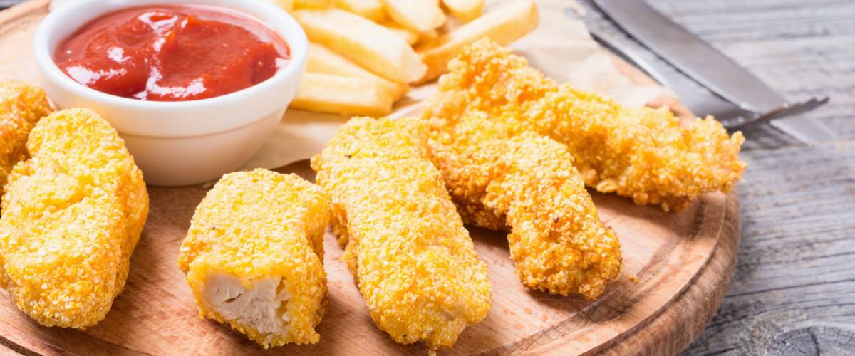 chicken strips and French fries on rustic wooden background