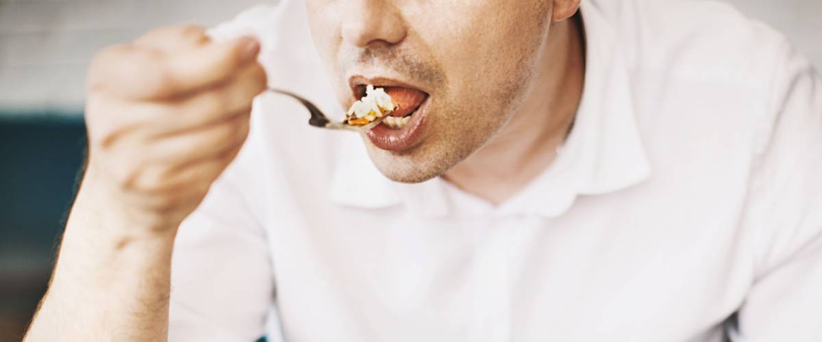 Unrecognizable man eating lunch. Front view. Horizontal.