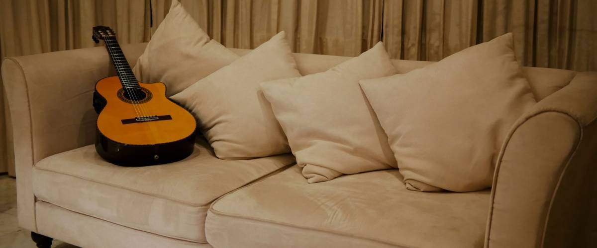 A guitar resting on a sofa in the living room after being used in a recording