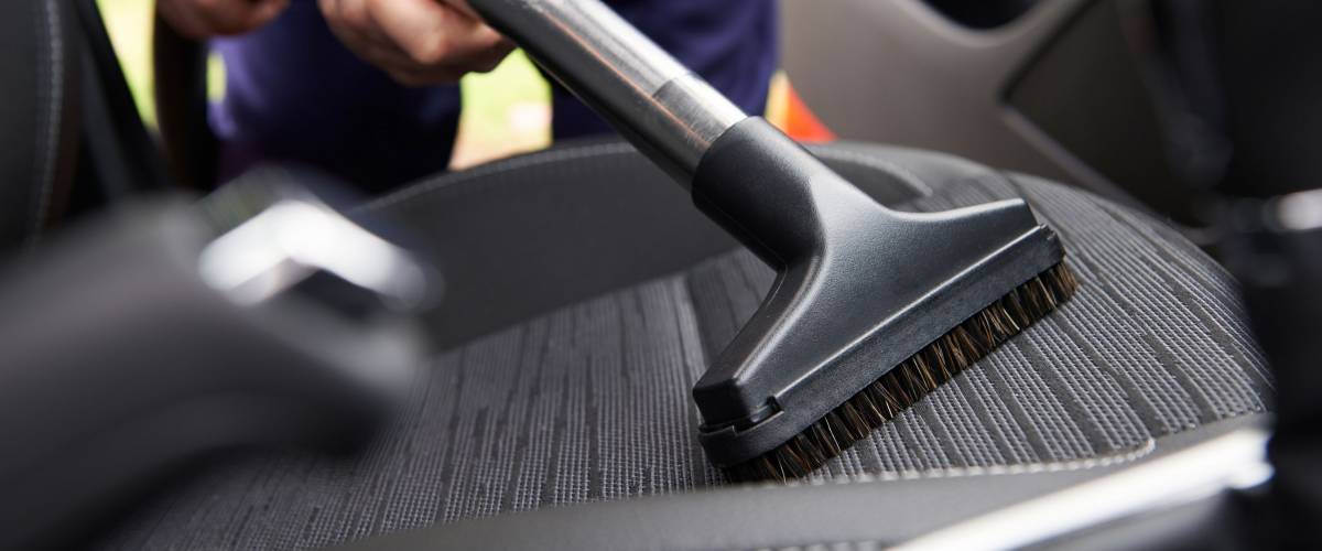 Man vacuuming seat of car