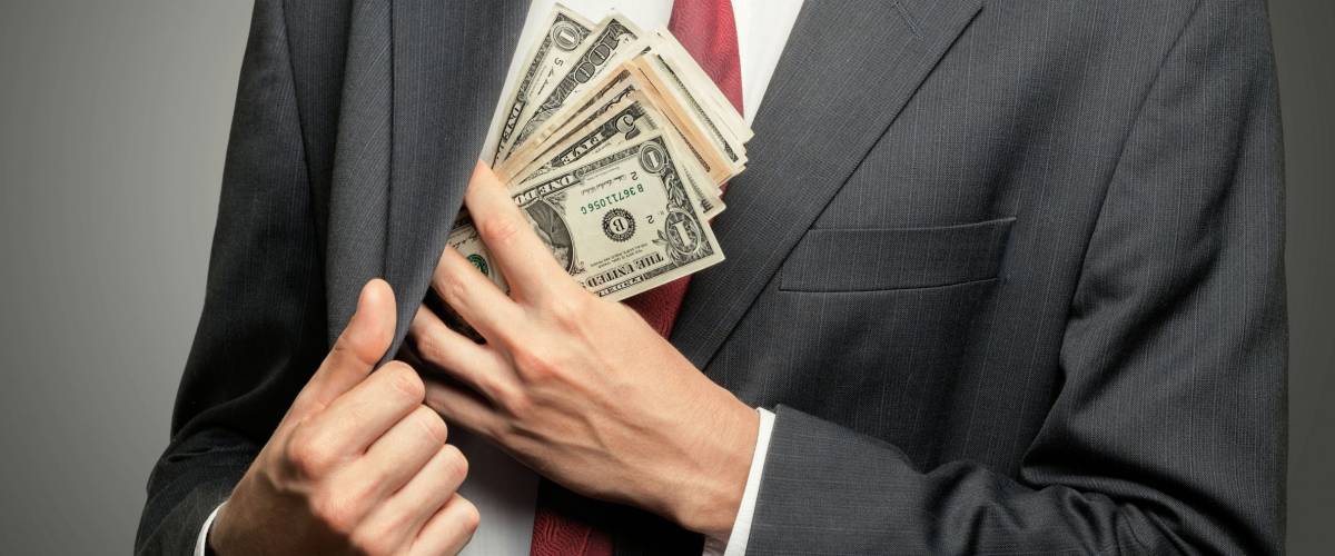 Man shoving one dollar bills into jacket
