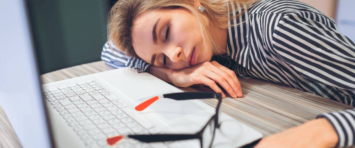 freelancer girl was tired and fell asleep at work at a desk near a white notebook. Break at work, quiet hour
