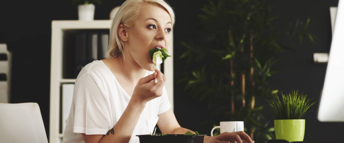 Multipurpose woman eating and using a computer at office