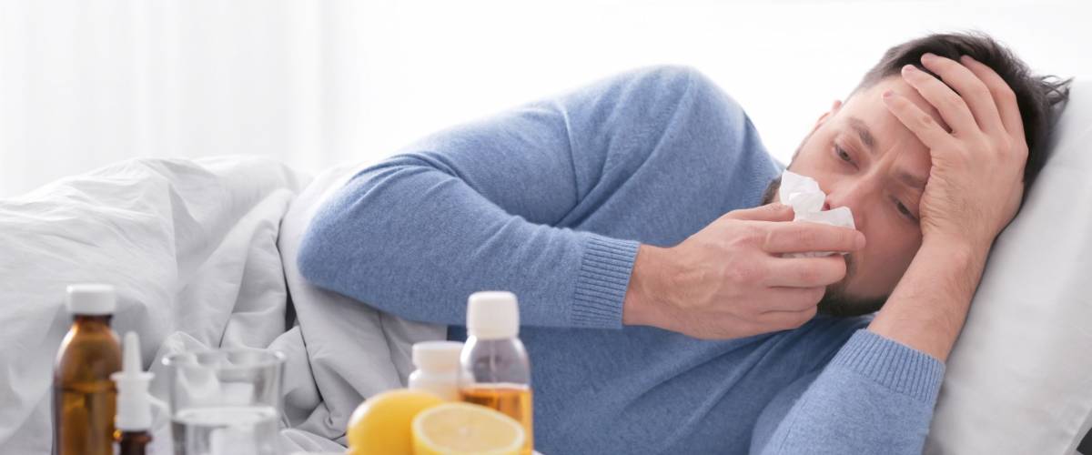 Young ill man lying in bed at home