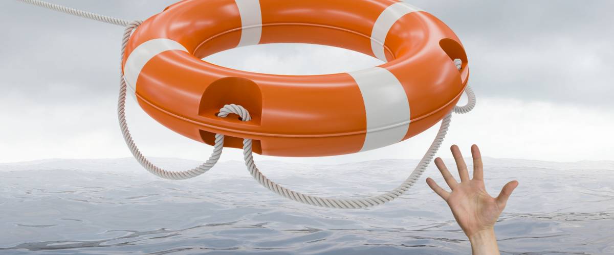 Man is drowning in ocean and is catching life buoy.