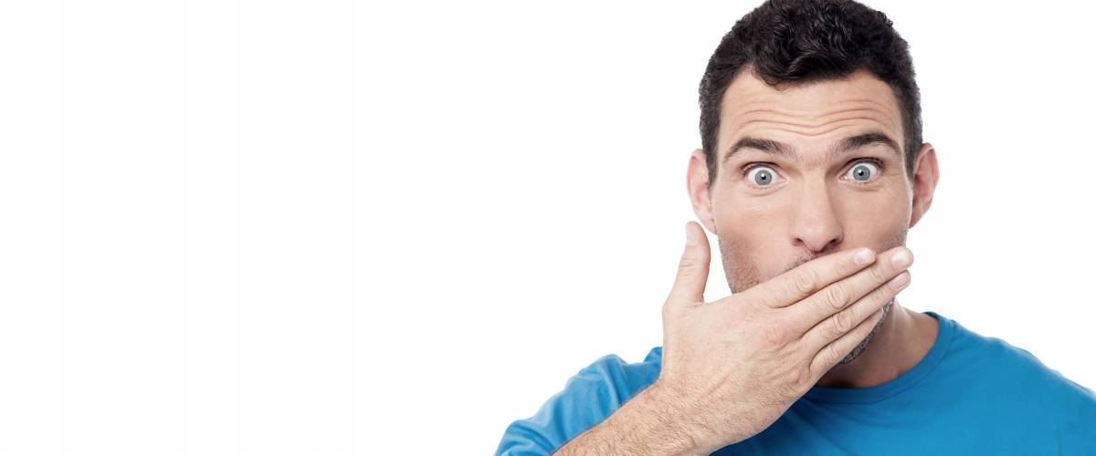Casual man covering his mouth with hand over white