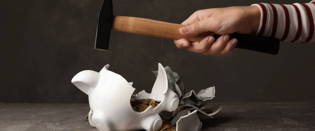 Woman breaking piggy bank with hammer