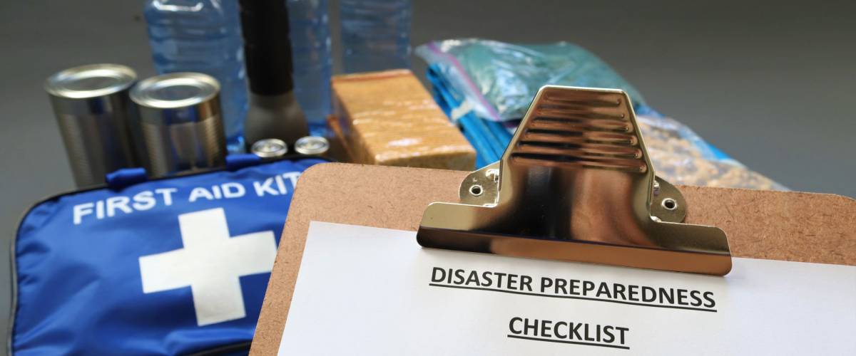Disaster preparedness checklist and first aid items in background
