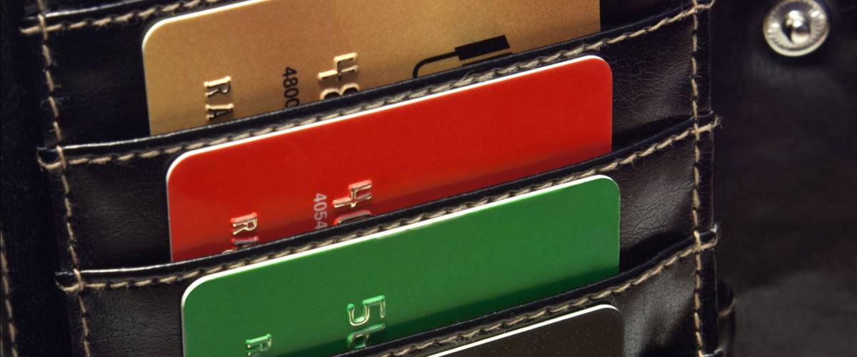 Several Multicolored red green black blue gold credit cards in the black wallet.