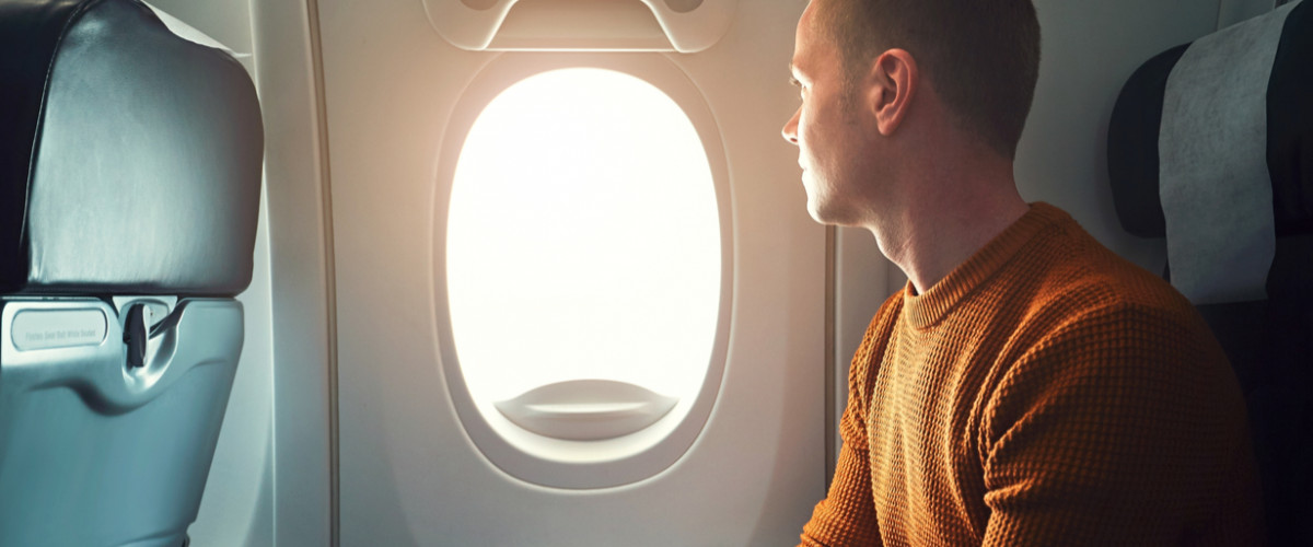 Curious young traveler looks out window of airplane