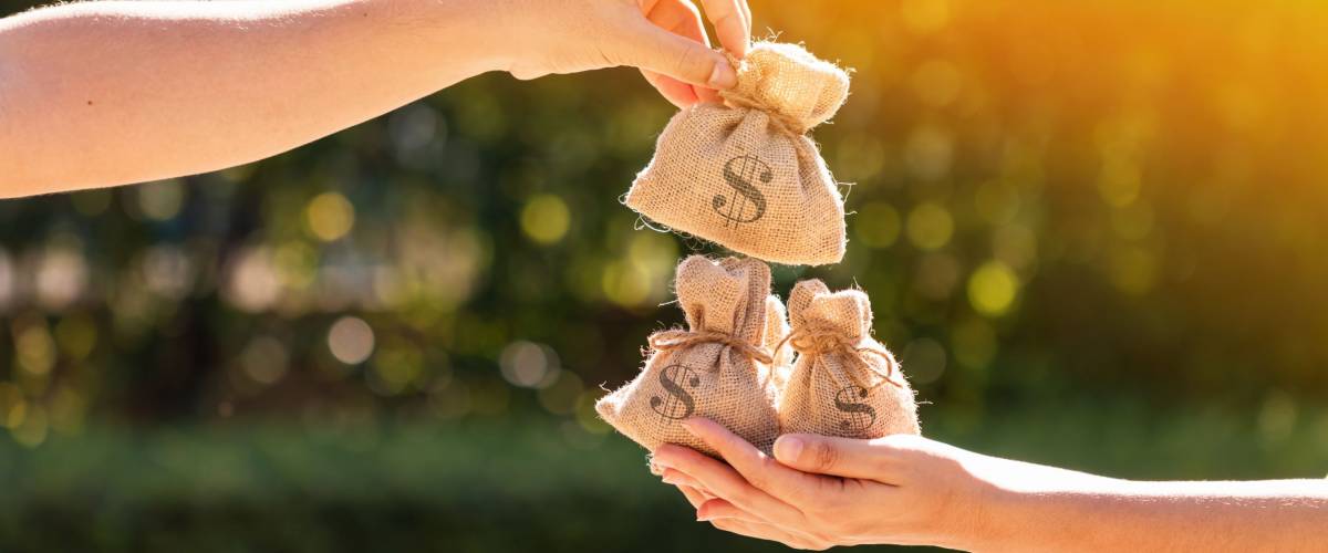 money bags held by hands in a park. loaning money to a friend concept.