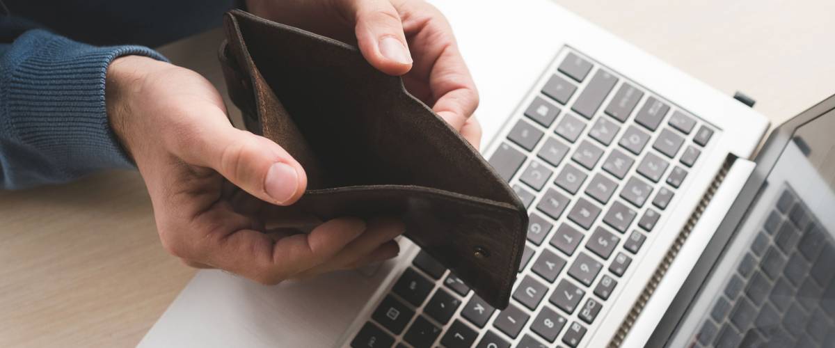 empty wallet over a laptop. internet scam concept.