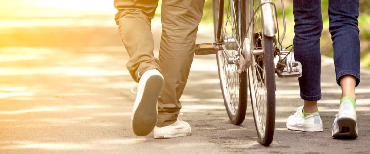 Back view of young couple walking together with bicycle