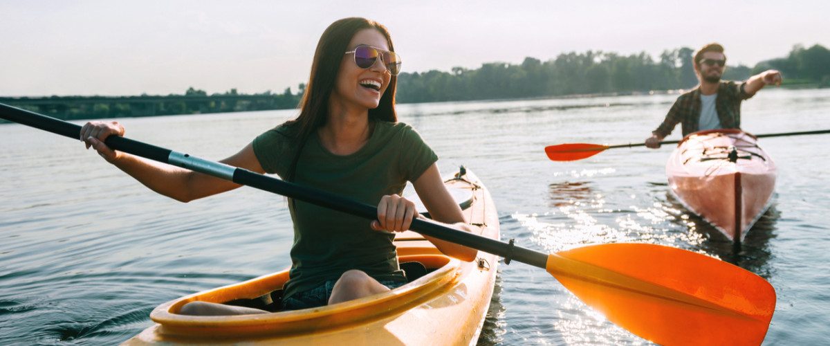 Couple kayaking together. Young couple kayaking on lake together and smiling.