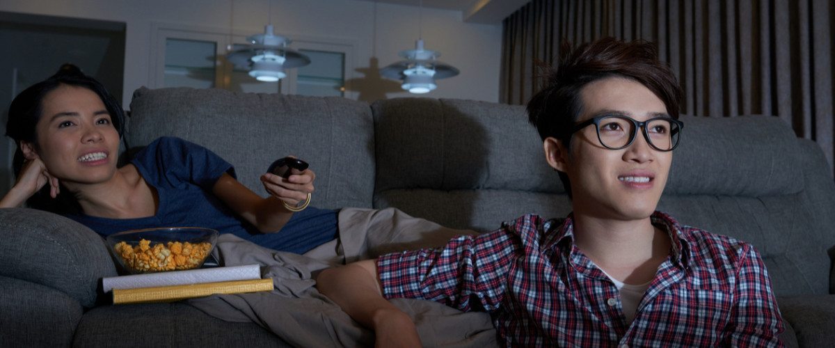 Young couple watching TV at home together