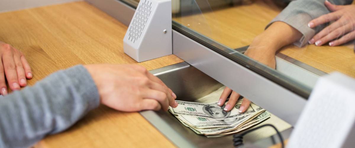 people, withdrawal, saving and finance concept - clerk giving cash money to customer at bank office or currency exchanger