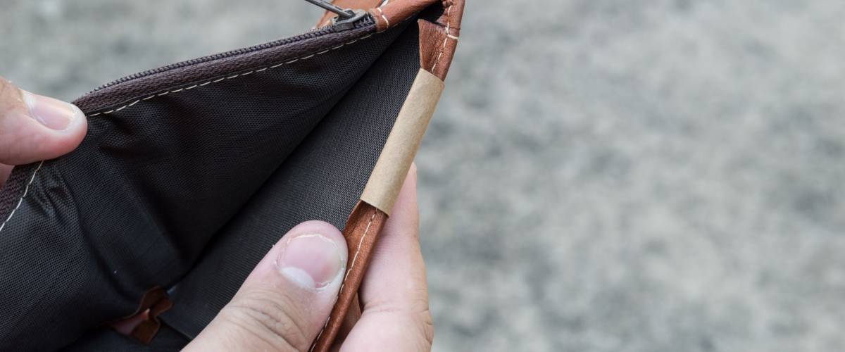 Broke man showing his brown leather wallet with no money on a poor economy day