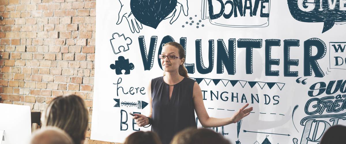 Leader of a charity running a meeting in front of a banner that says
